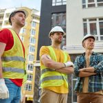 three-men-looking-aside-construction-site_259150-57679